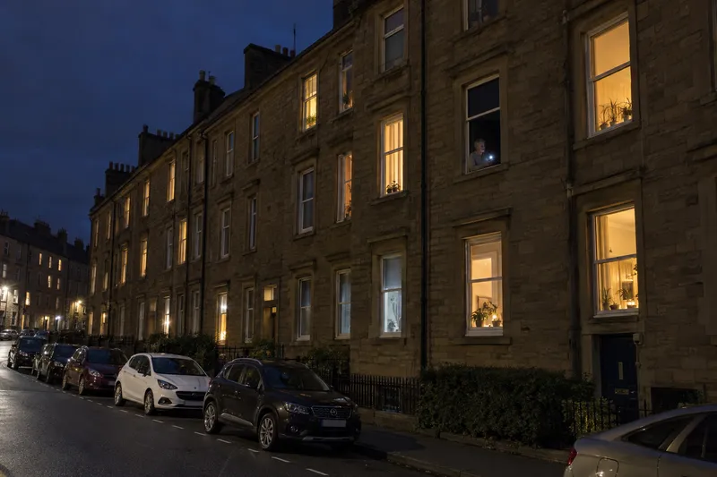 One dark flat window in a lit Dundee tenement street at night