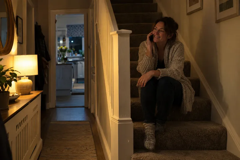 Woman on the stairs at night phoning an emergency electrician
